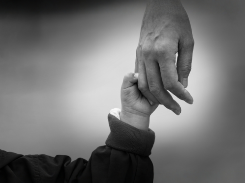 Adult holding a child's hand (black and white)