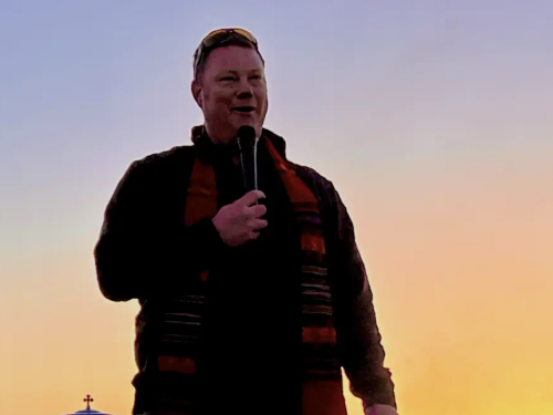 Rev Andrew Black with microphone at Caja at sunrise