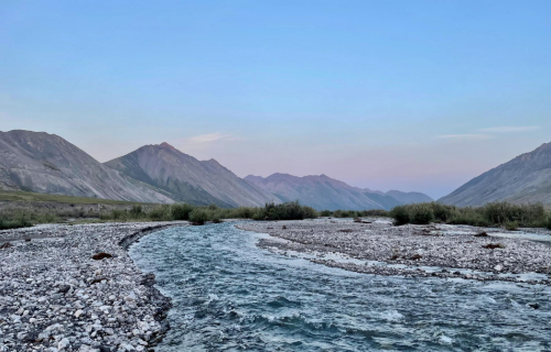 Artic landscape with mountains in background and rocky river in foreground