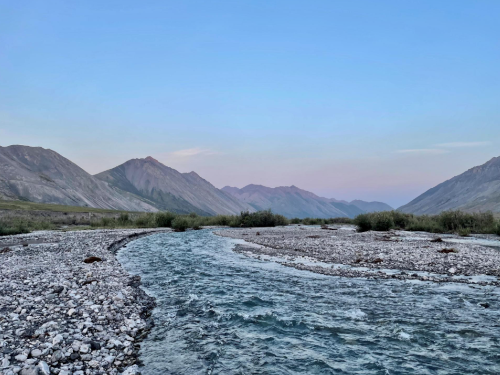 Artic landscape with mountains in background and rocky river in foreground