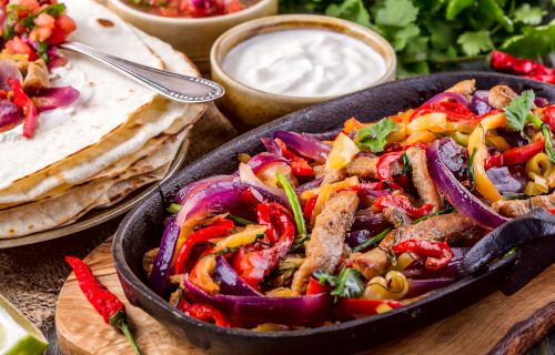 Plate of fajitas with tortillas and condiments on the side