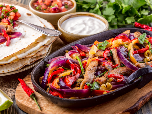 Plate of fajitas with tortillas and condiments on the side