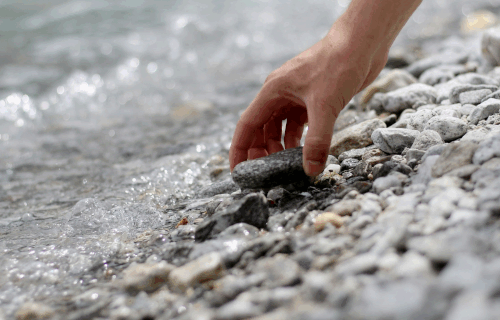 Hand picking up stone at the beach