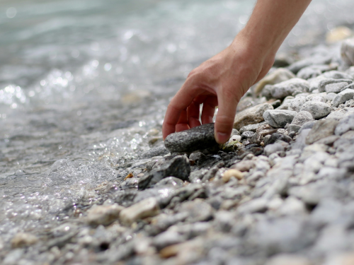Hand picking up stone at the beach