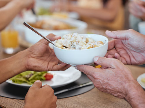 Hands passing food at a table with others