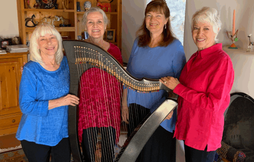 Four harpists surrounding a large harp