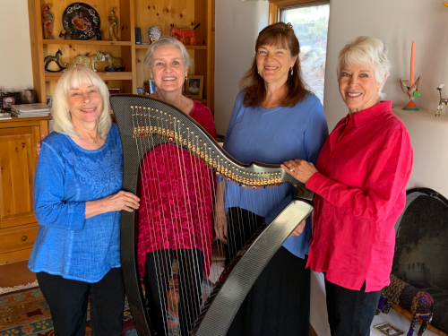 Four harpists surrounding a large harp