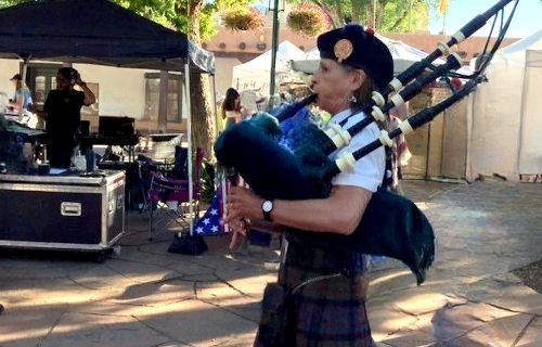 Bagpiper walking down Santa Fe street playing bagpipe