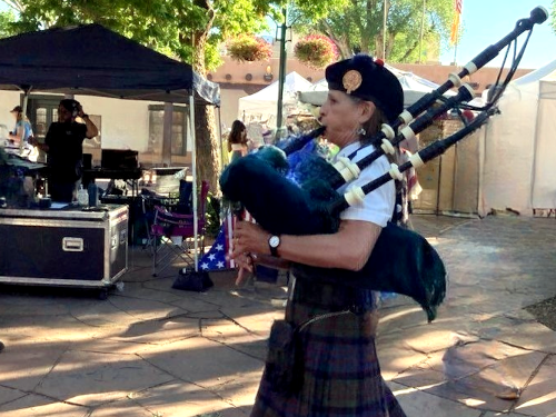 Bagpiper walking down Santa Fe street playing bagpipe
