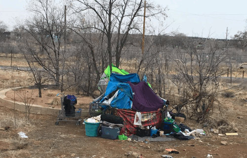 Makeshift tent out in rurual area surrounded by belongings