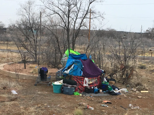 Makeshift tent out in rurual area surrounded by belongings