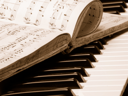 Close up of book of music on top of piano keys