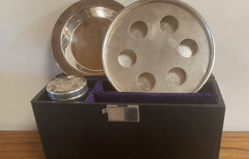 Open communion kit with metal cupholders and tray showing