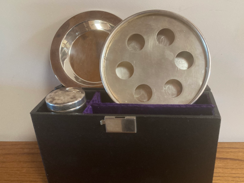 Open communion kit with metal cupholders and tray showing