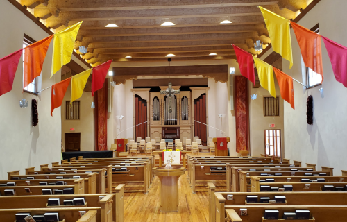 FPC sanctuary decorated for Pentecost with colorful flags and red banners