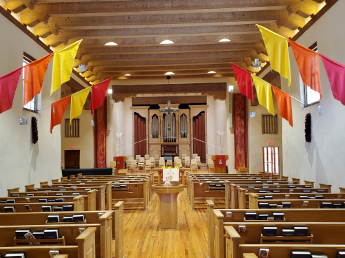 FPC sanctuary decorated for Pentecost with colorful flags and red banners