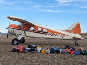 Small plane with camping gear laying on ground beside it