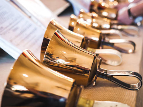 A series of handbells laying in from of sheet music