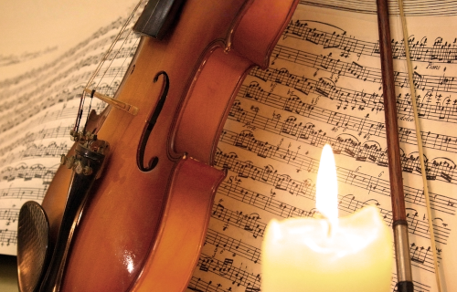 Violin and music with lit candle