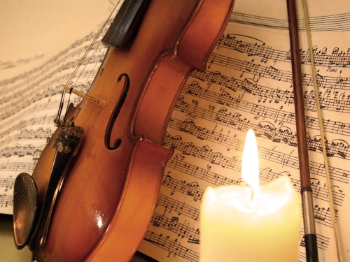 Violin and music with lit candle