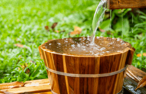 Water flowing into a wooden bucket
