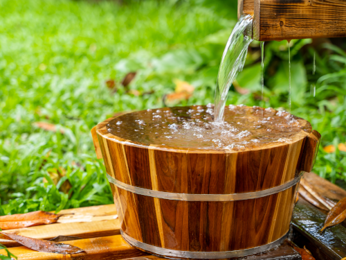 Water flowing into a wooden bucket